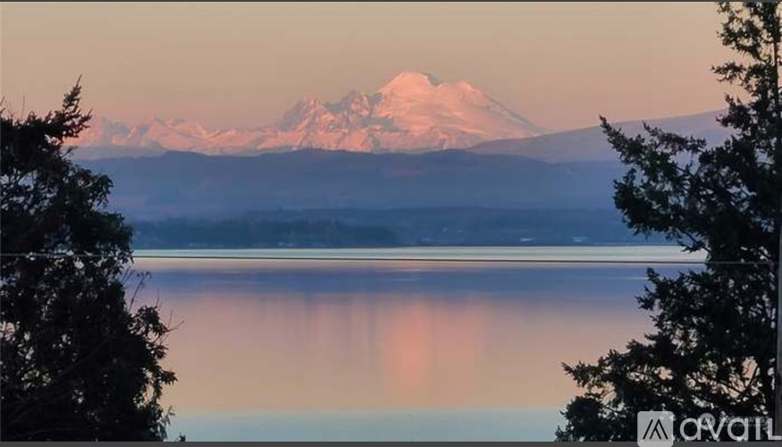 A mountain with a snow cap is reflected in the water below.