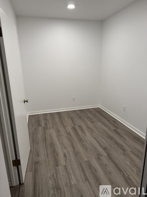 A room with wooden flooring and white walls.