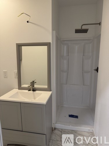 A bathroom with a sink, mirror, and shower.