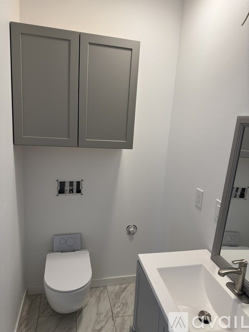 A bathroom with a toilet, sink and cabinets.