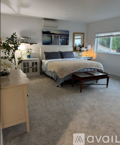 A bedroom with a bed, nightstand, and a window.