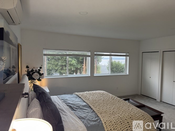 A bedroom with a large bed and a window overlooking trees.