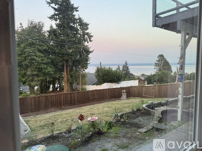 A backyard with a wooden fence and a view of the ocean.