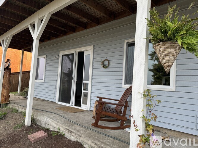 A porch with a rocking chair and a plant hanging from the ceiling.