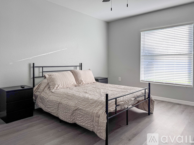 A bedroom with a bed, nightstand, and window with blinds.
