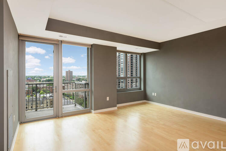 A spacious room with wooden floors and a view of the city through the windows.