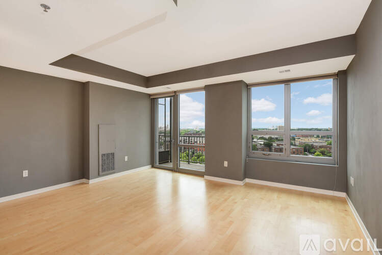A spacious room with wooden floors and large windows overlooking a cityscape.