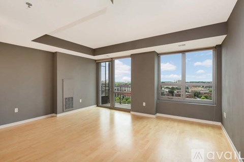 A spacious room with wooden floors and large windows overlooking a cityscape.