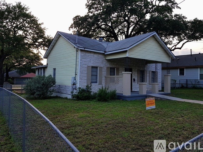A house with a fence and a sign in front of it.