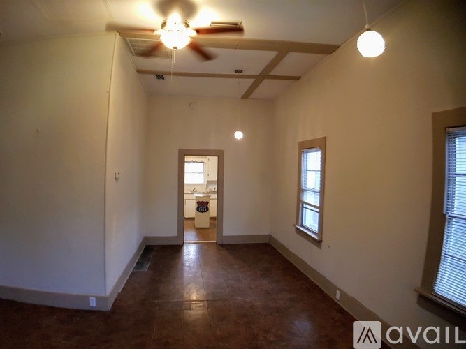 A room with a ceiling fan and two windows.