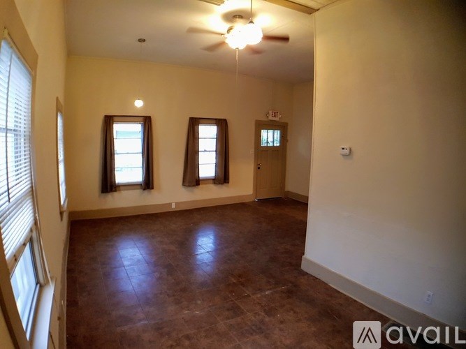 A room with brown flooring and a ceiling fan.