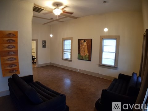 A living room with two black couches and a painting of a dog on the wall.