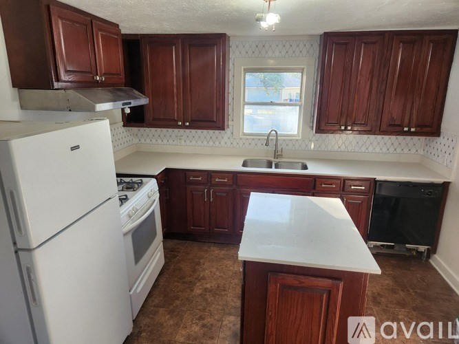A living room with a black couch and a brown floor.