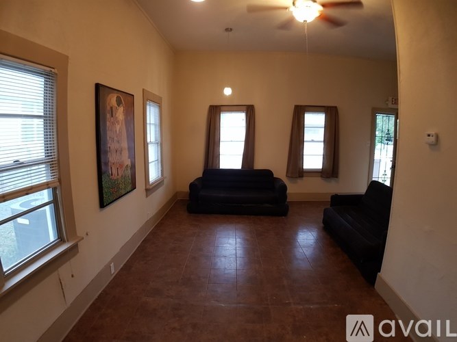 A living room with a black couch and a fan.