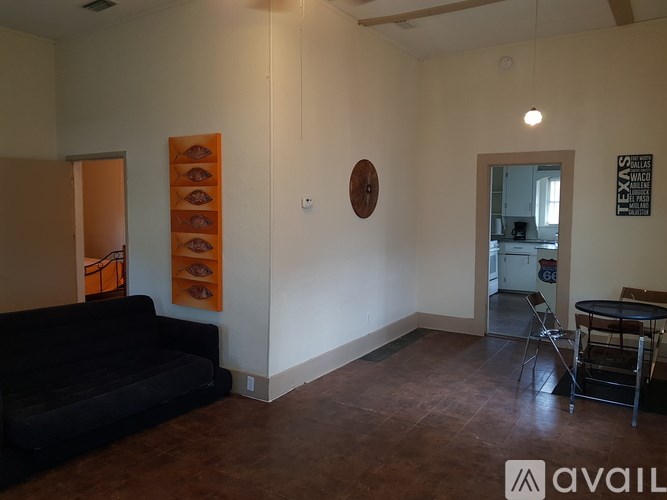 A living room with a black couch and a brown floor.