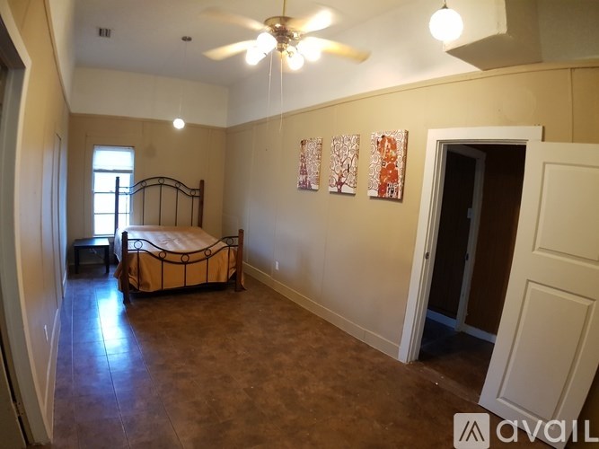 A bedroom with a bed, a ceiling fan, and a door.