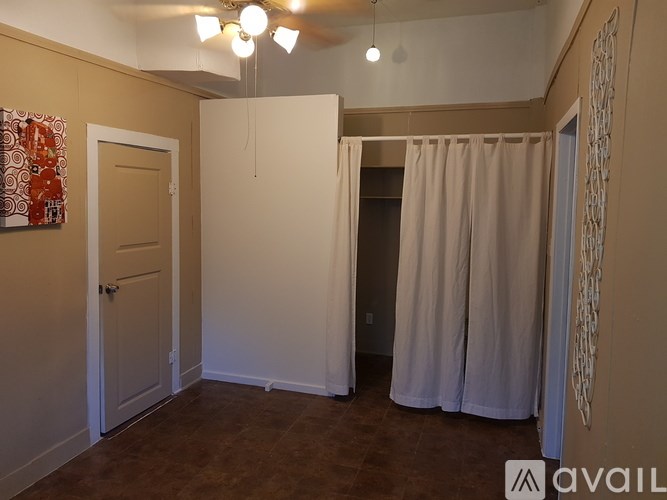 A room with a door, a window with curtains, and a wall art.