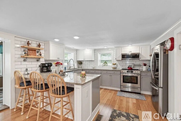 A kitchen with a white countertop and wooden chairs.