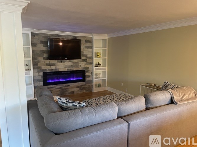 A living room with a grey couch and a stone fireplace.