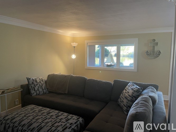 A living room with a grey couch and a patterned ottoman.