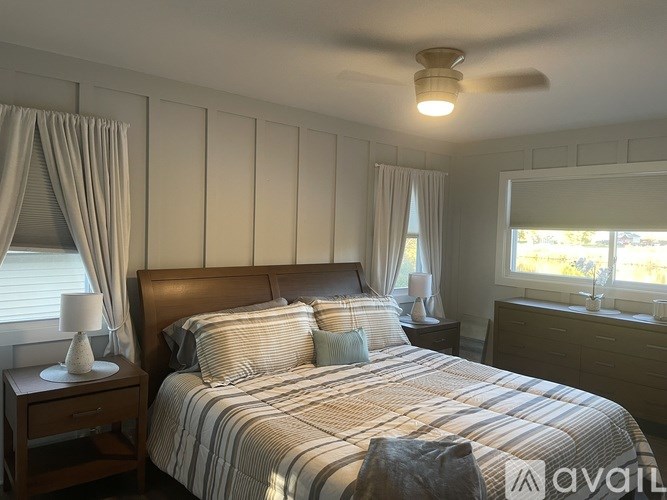 A well-lit bedroom with a large bed and a ceiling fan.