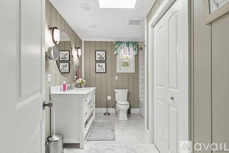 A bathroom with a toilet, sink, and pictures on the wall.