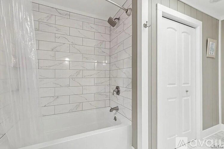 A white bathroom with a marble tile shower.