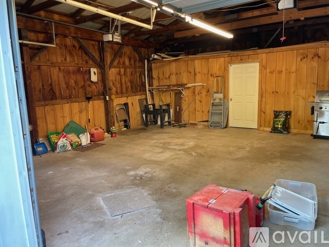 A room with wooden walls and a concrete floor has a ladder and a white door.