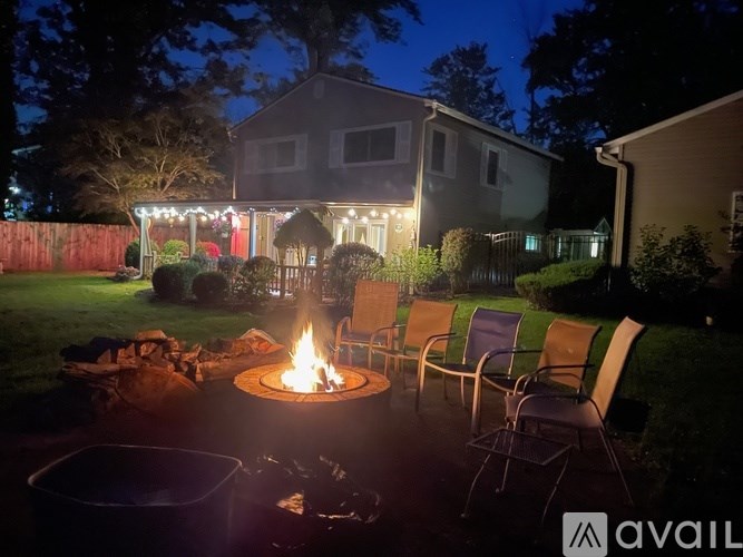 A fire pit in a backyard with chairs around it.