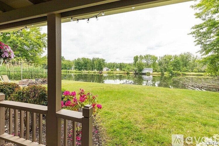 A view from a porch looking out to a lake and greenery.