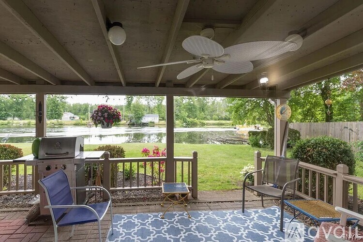 A patio with a fan, chairs and a table.