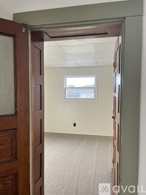 A room with a window and a carpeted floor.