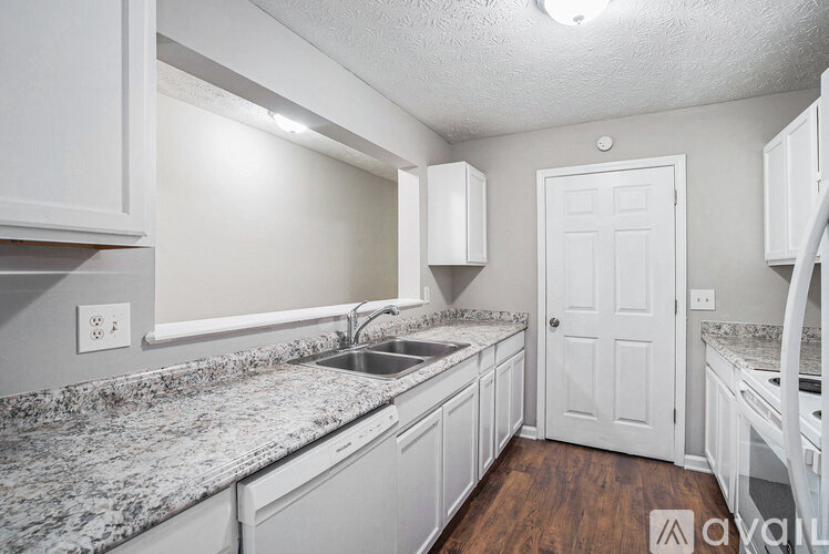 A kitchen with white cabinets and a granite countertop.