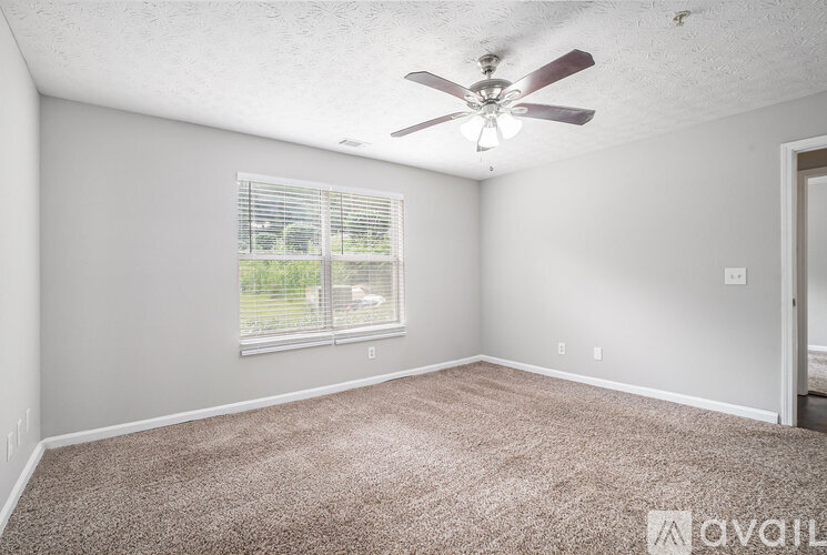 A room with a ceiling fan and carpeted floor.