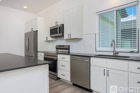A kitchen with white cabinets and a black countertop.