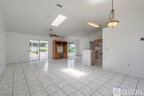 A spacious living room with a kitchen in the background.