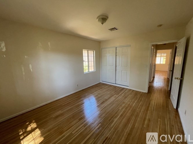 A room with wooden floors and white walls, with a door on the right side.