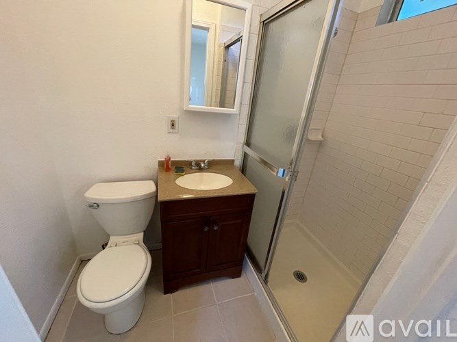 A bathroom with a toilet, sink, and mirror.