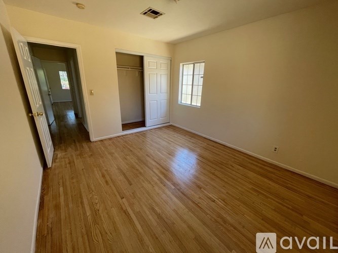 A room with wooden flooring and two doors, one of which is open.