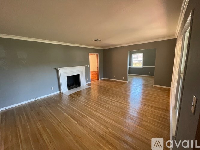 A room with wooden flooring and a fireplace is available for rent.