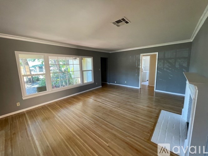 A room with wooden flooring and a large window.