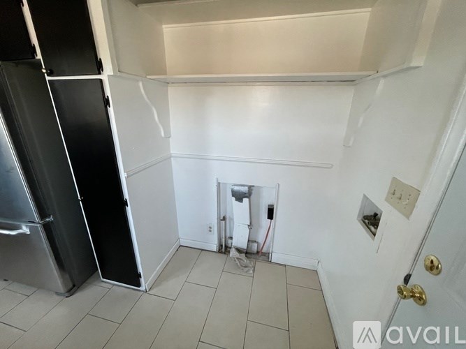 A small kitchen with a refrigerator and a door open to a hallway.