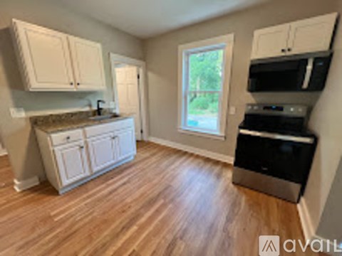 A kitchen with white cabinets and a black microwave.