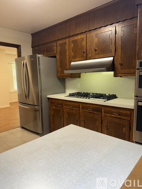 A kitchen with wooden cabinets and a stainless steel refrigerator.