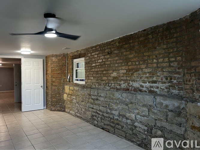 A room with a brick wall and a ceiling fan.