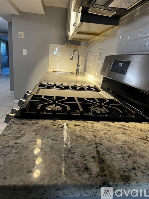 A modern kitchen with a granite countertop and a black stove top.