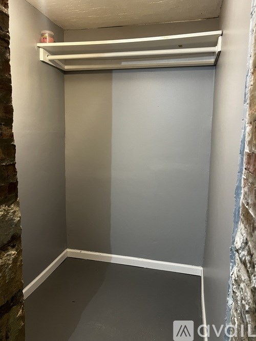 A small, empty room with a brick wall on the left and a white wall on the right.