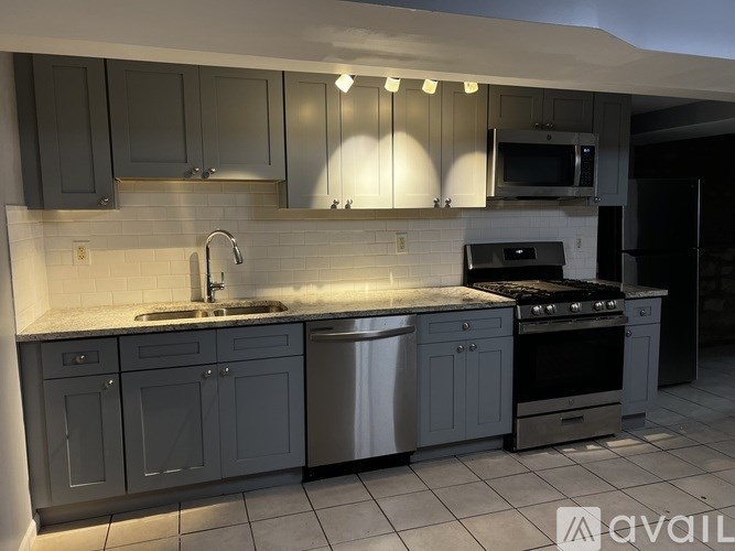 A kitchen with grey cabinets and a white countertop.