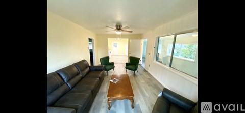 A living room with a black leather couch and a wooden coffee table.