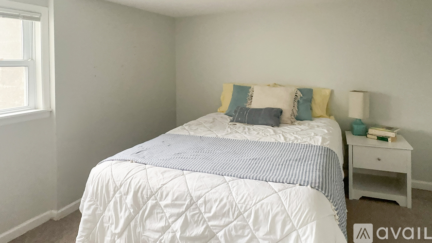 A bedroom with a white bed and a small white nightstand.